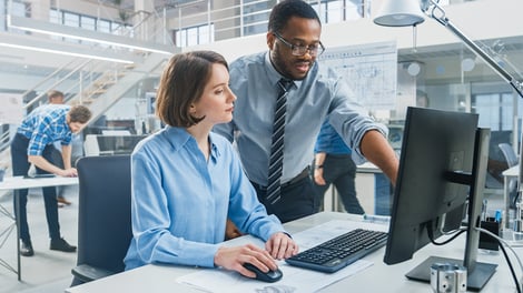 Man showing co-worker something on their computer monitor