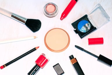 Cosmetic products laid out in a circle with a make up powder compact in the middle.