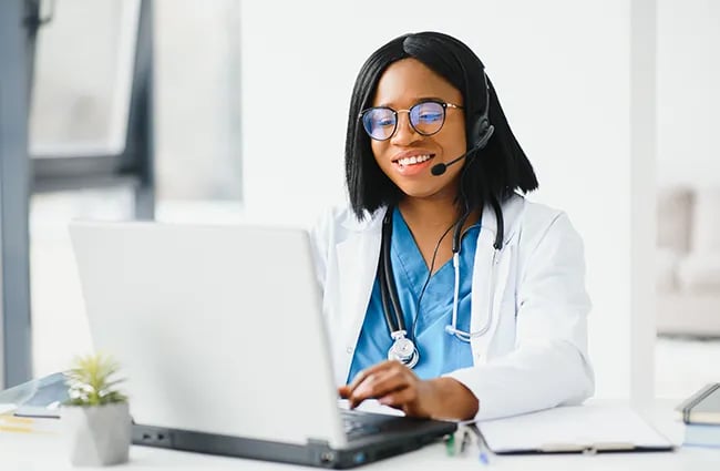 health-care-worker-wearing-headset-working-on-laptop-ss-1829353274-650x425