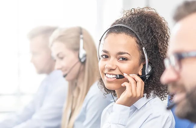 Row of customer service professionals wearing headset one person smiling at camera