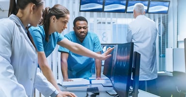 Health care professionals reviewing computer monitors inside an examination room