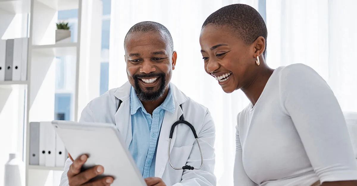 Health care worker and patient smiling reviewing clipboard