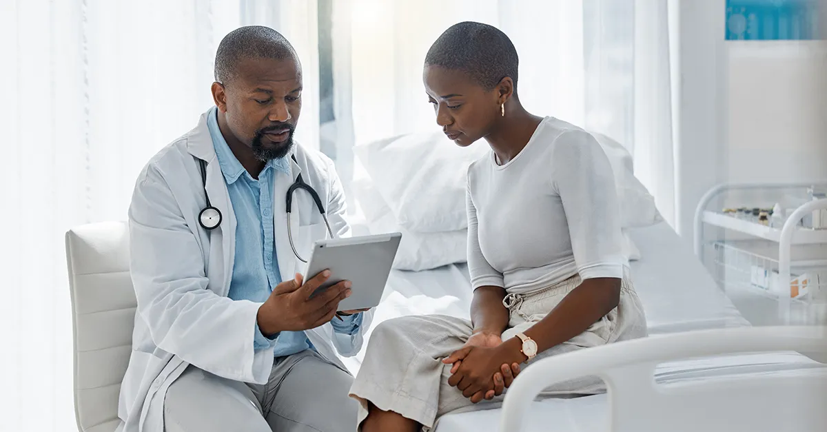 Healthcare worker showing a woman details on a tablet device.